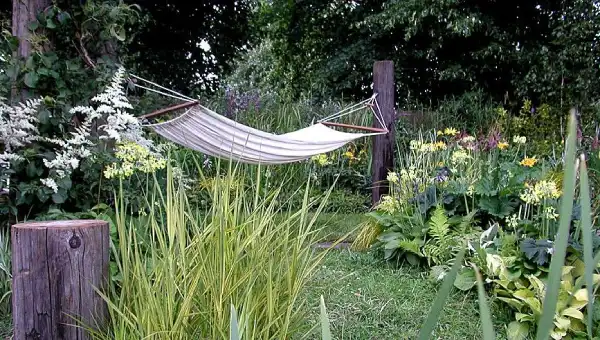 "Relaxing hammock set up in a lush garden with trees and plants creating a serene atmosphere."