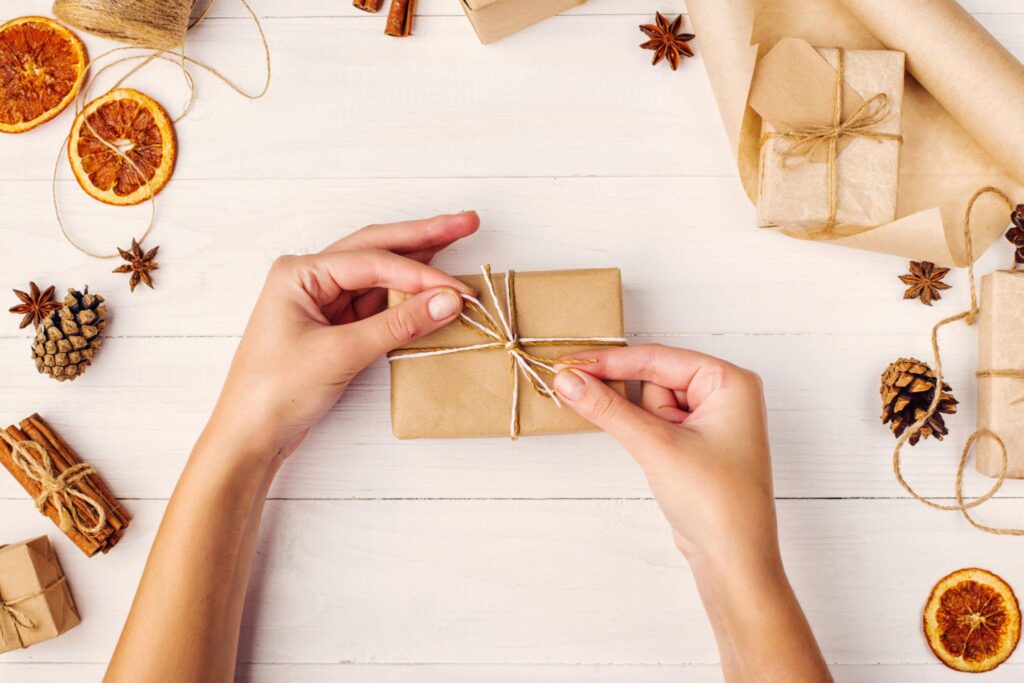 Beginner wrapping a Halloween gift with kraft paper and orange twine